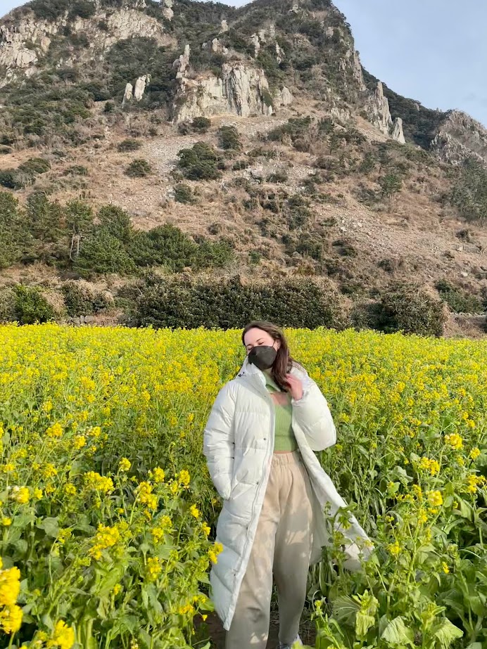 Hallie in a yellow flower field in front of a mountain
