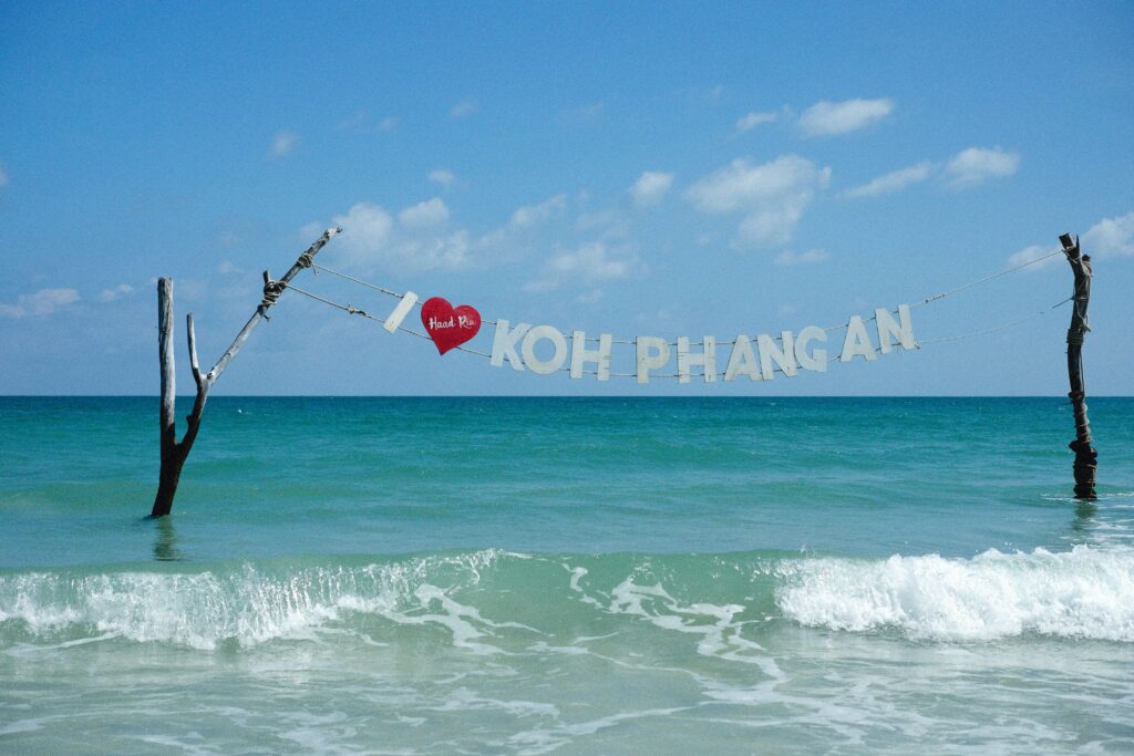 two sticks in the ocean with a banner saying I love Koh Phangnan