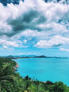 view from above of the bright blue waters and hilly coast of koh samui